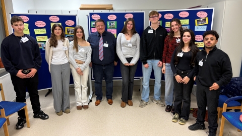 Acht junge Menschen mit Bürgermeister vor Stellwand 