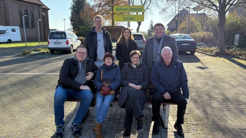 Gruppe von Menschen, die um eine Bank versammelt ist.