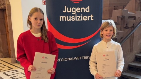 Foto zeigt 2 Kinder mit Urkunden von einem Musikwettbewerb