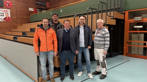 Fünf Männer vor Tribüne aus Holz