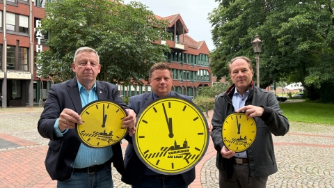 Drei Männer mit gelben Uhren und der Zeiger ist auf 5 vor 12. 