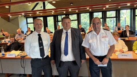 Drei Männer vor Publikum im Ratssaal