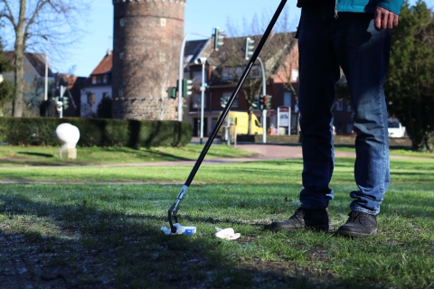 Person, die mit einem Greifer Müll aufhebt