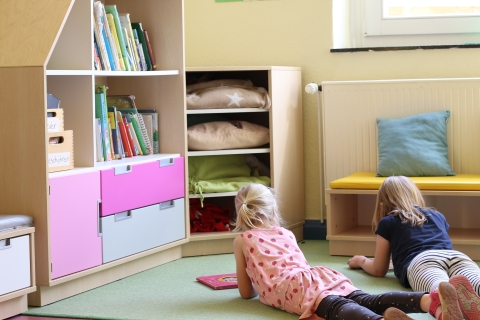 Kinder lesen vor einer Bücherwand