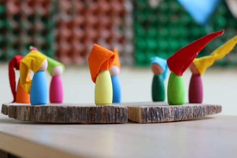 Bunte Figuren mit Zwergenmützen auf einem Holzbrett