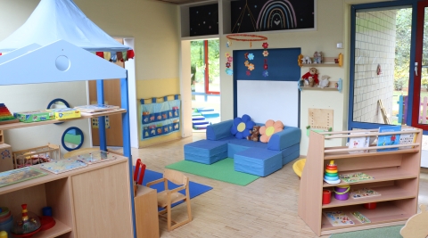Gruppenraum des Familienzentrums mit Blumenkissen und Spielen.