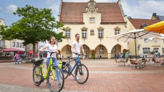 Radfahrer auf dem Marktplatz schiebend 