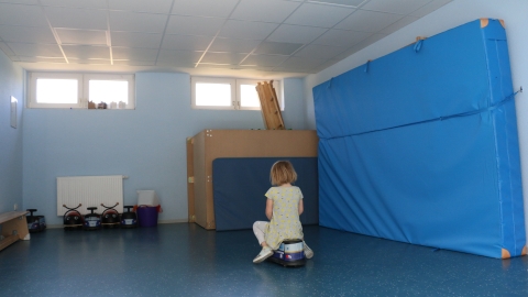 Kind auf Rutscheauto in einer Turnhalle