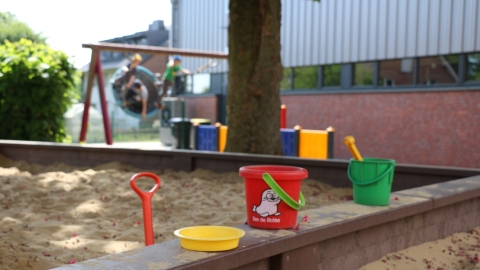 Sandkasten mit bunten Eimern und Sandspielzeug