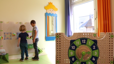 Zwei Kinder stehen an einer Spielwand