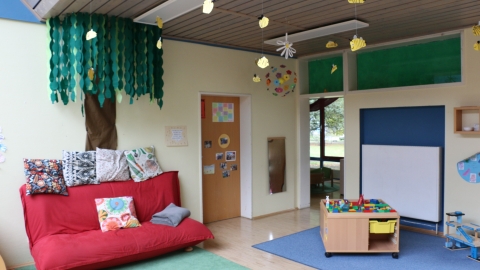 Gruppenraum mit rotem Sofa und Girlanden 