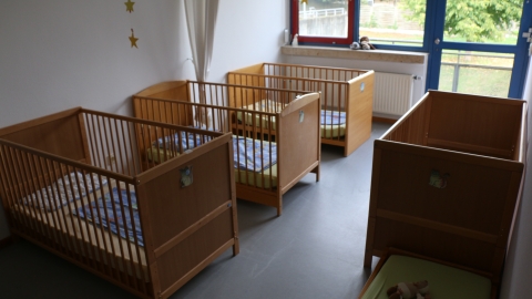 Mehrere Kinderbetten in abgedunkeltem Raum 