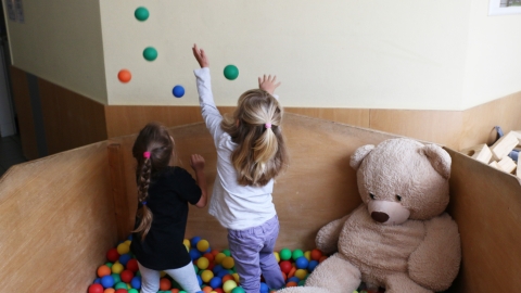 Zwei Mädchen werfen bunte Bälle in die Luft 