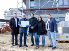 Fünf Menschen mit Urkunde auf Baustelle