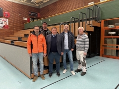 Fünf Männer vor Tribüne aus Holz