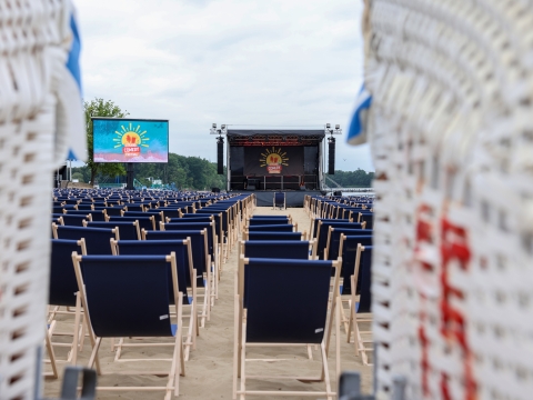 Blick zwischen zwei Strandkörben hindurch auf eine Bühne 