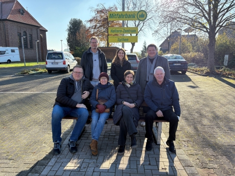 Gruppe von Menschen, die um eine Bank versammelt ist.