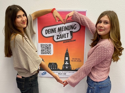 Zwei Mädchen bilden Herz um Plakat zur Beteiligung