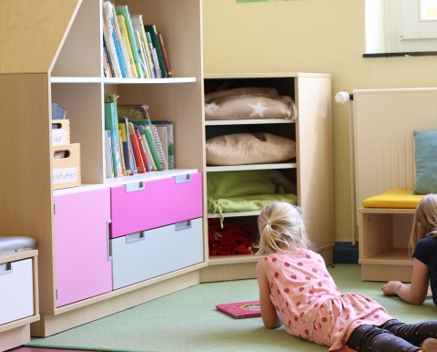Kinder lesen vor einer Bücherwand