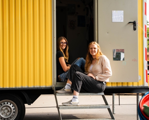 in der Tür des Bauwagen sitzen 2 junge Frauen 