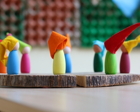 Bunte Figuren mit Zwergenmützen auf einem Holzbrett